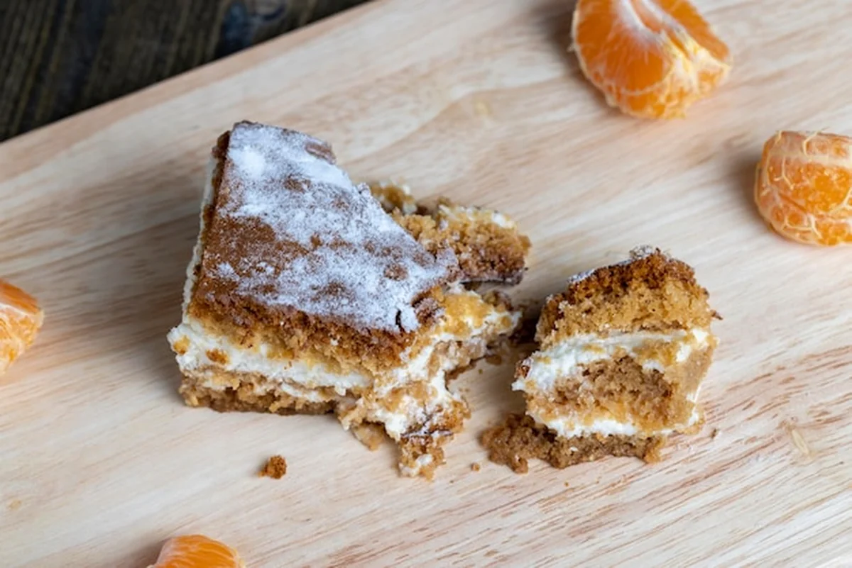 Kawałek ciasta miodowego z kremem waniliowym i mandarynkami