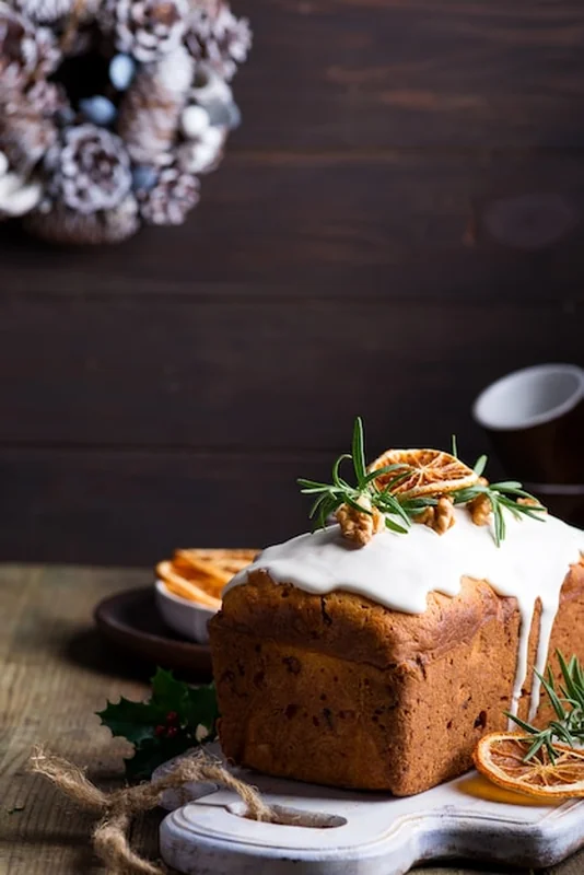 Ciasto owocowe z polewą, orzechami i pomarańczą na drewnianym blacie