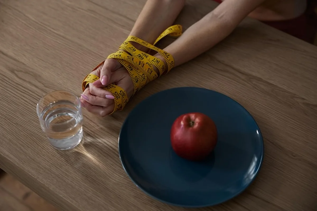 Związane ręce kobiet z taśmą pomiarową na stole w kuchni