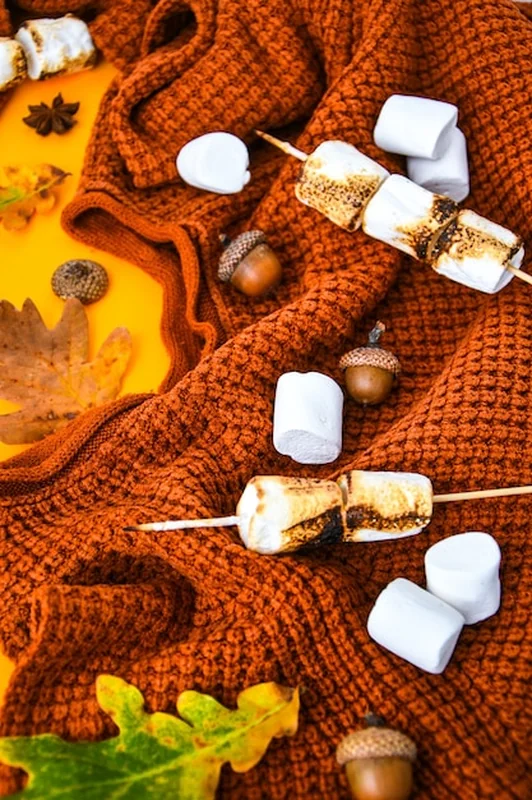 Jesienne mieszkanie z pomarańczowym swetrem i liśćmi na żółtym tle