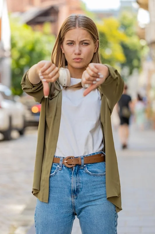 Młoda kobieta na ulicy pokazująca kciuk w dół