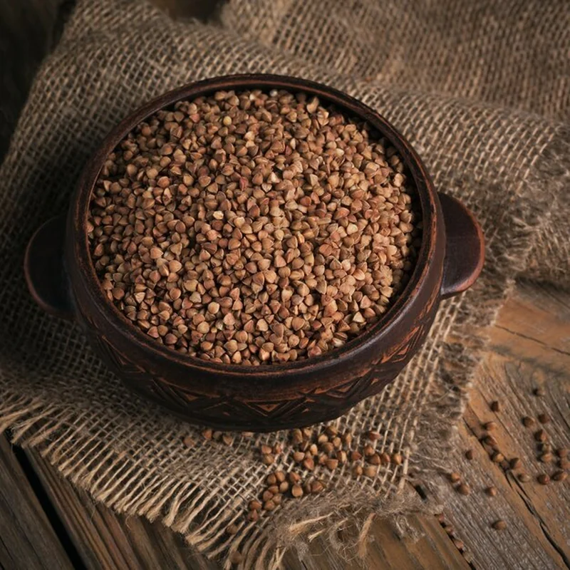 Surowe ziarno gryki w misce na drewnianym blacie