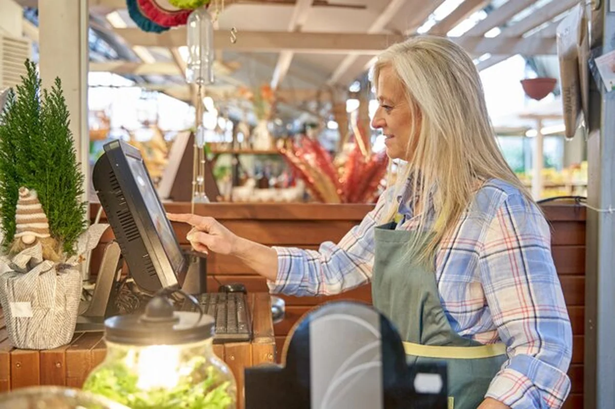 Kobieta kasjerka w sklepie dotyka ekranu dotykowego, aby oznaczyć produkty