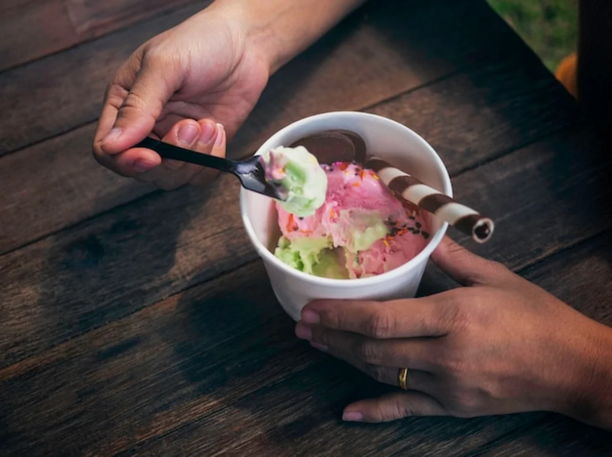 Biały kubek z tajskim lodem truskawkowo-cytrynowym i kobietą