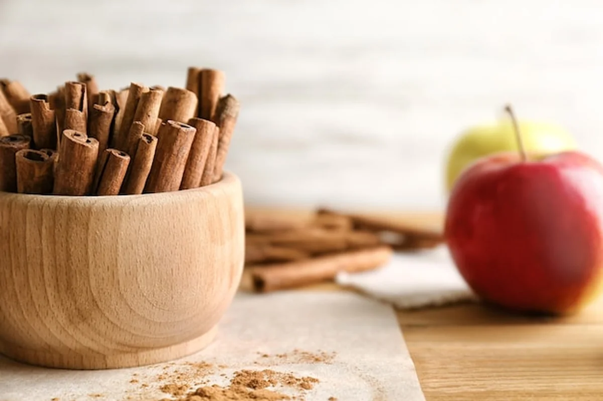 Miska z laskami cynamonu i jabłkami na stole