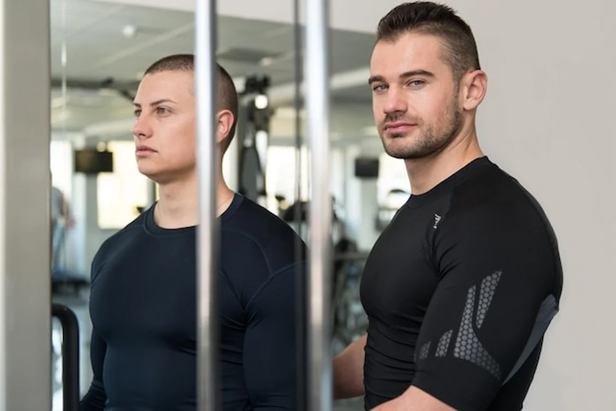 Mężczyzna trenuje biceps z trenerem na maszynie