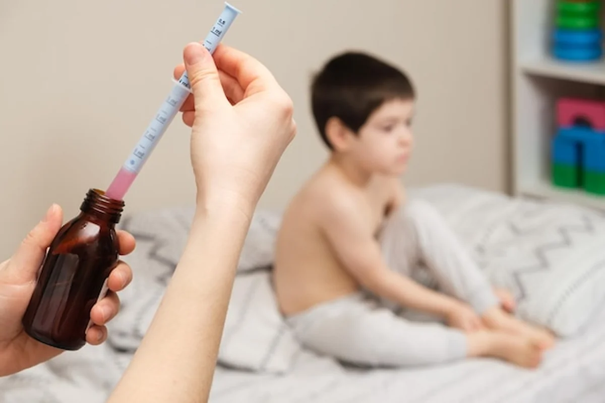 Pediatra podaje lek na kaszel w strzykawce miarowej