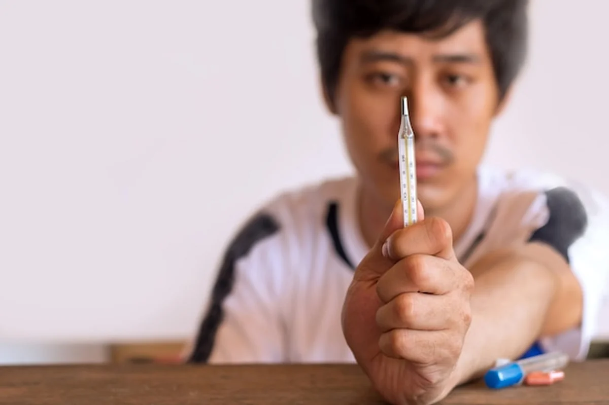 Chory mężczyzna z termometrem na białym tle