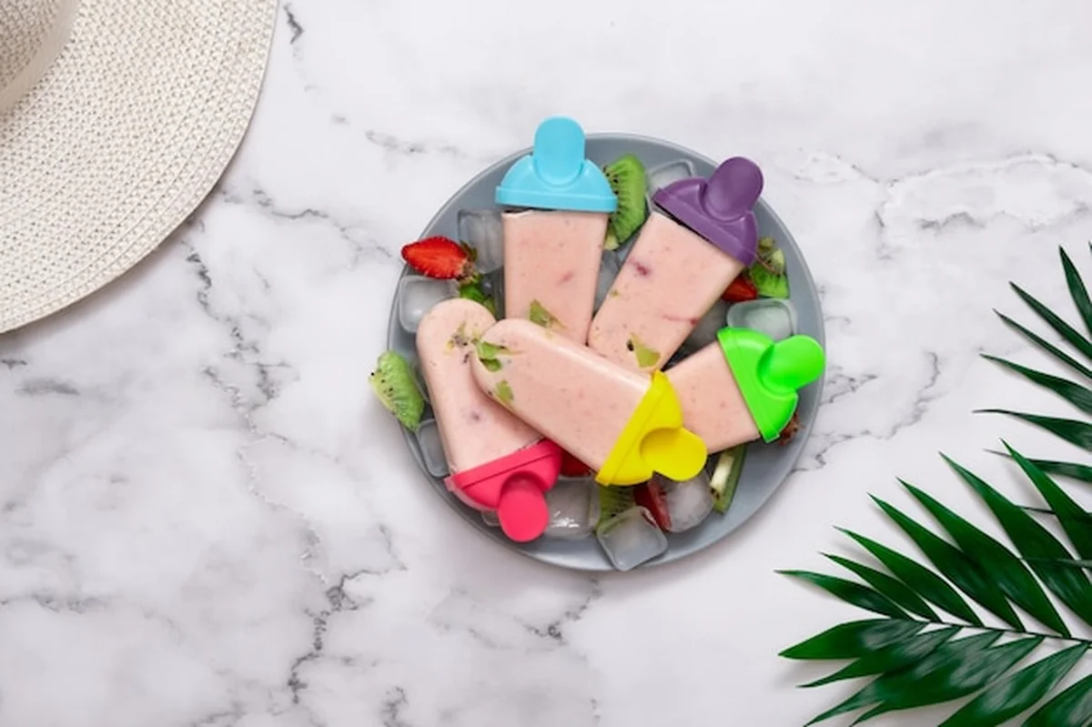 Domowe lody na talerzu z lodem, owocami i liśćmi palmowymi. Widok z góry. Koncepcja gorącego lata