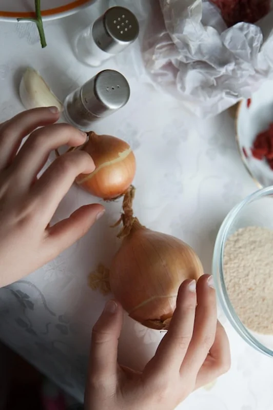 Przycięte ręce trzymające cebulę na stole