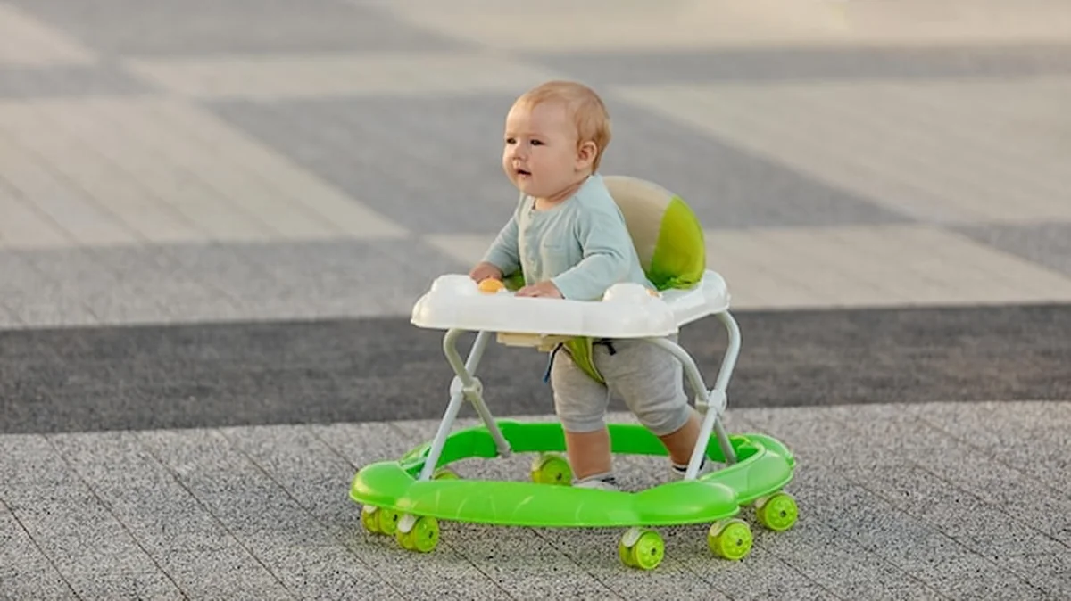 Dziecko uczy się chodzić na chodziku na świeżym powietrzu