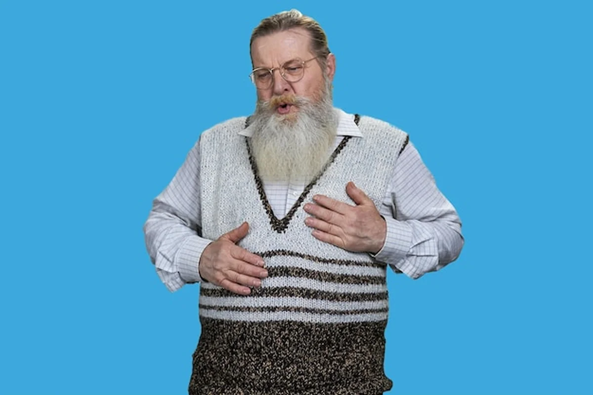 Stary człowiek z długą brodą odczuwający ból w klatce piersiowej