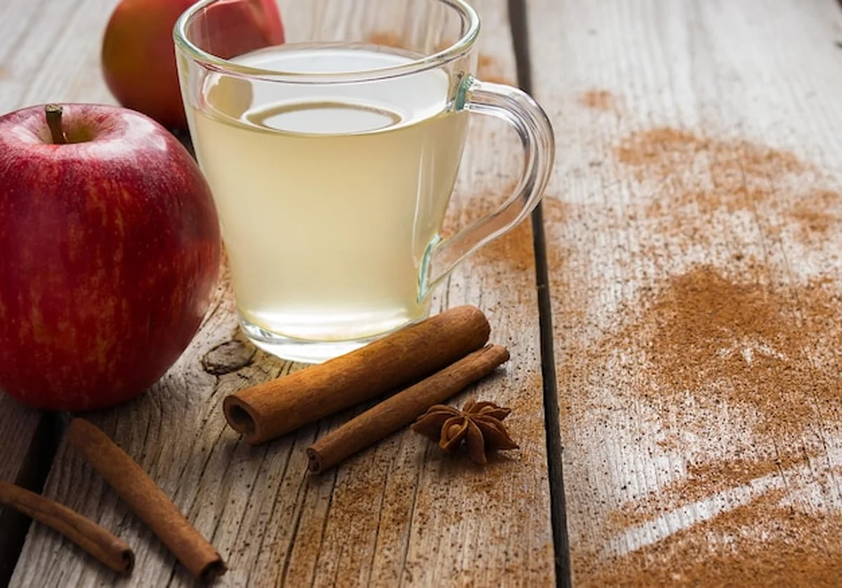 Świeży soczysty jabłkowy napój w filiżance i laski cynamonu