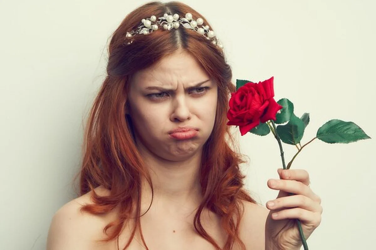 Młoda kobieta trzymająca różę na białym tle