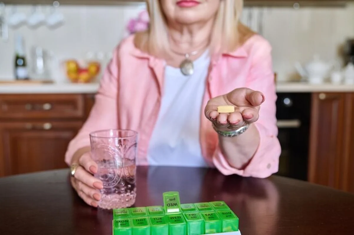 Starsza kobieta bierze witaminy z pudełka na pigułki codziennie