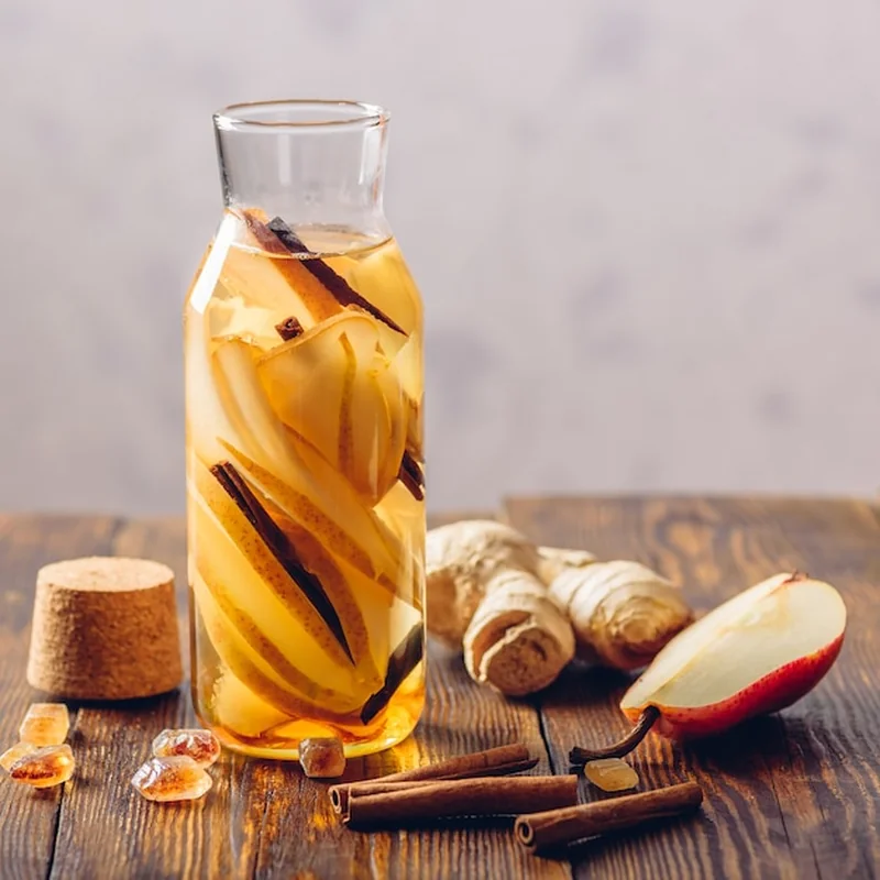 Butelka wody z plastrami gruszki, laską cynamonu, imbirom i ciemnym cukrem