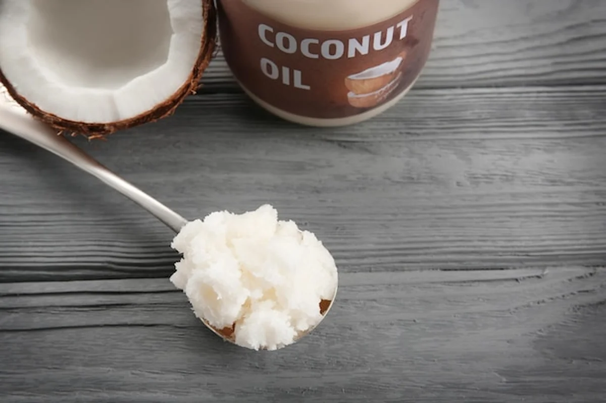 Metalowa łyżka ze świeżym olejem kokosowym na szarym drewnianym tle