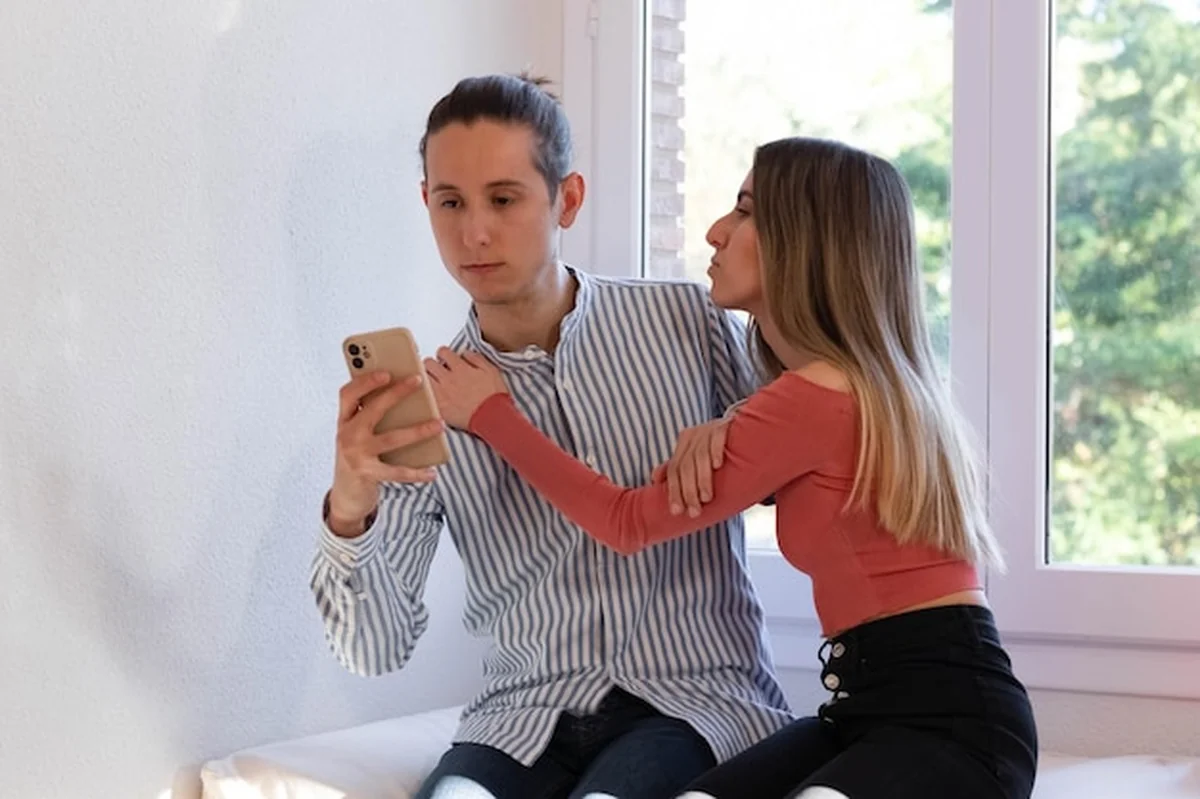 Mężczyzna odmawia pocałunku dziewczynie, gdy pisze ze smartfona